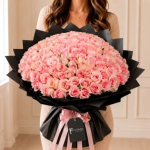 100 Pink Roses Bouquet featuring luxurious soft pink roses with fresh green fillers, elegant black wrapping and white ribbon, perfect premium floral gift for romantic occasions and special celebrations.