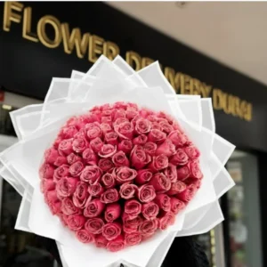 100 Pink Roses Bouquet featuring luxurious soft pink roses with fresh green fillers, elegant black wrapping and white ribbon, perfect premium floral gift for romantic occasions and special celebrations.